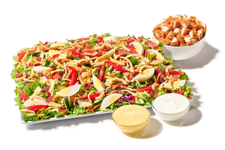 Zaxby’s Cobb Zalad® Platter featuring crispy Chicken Fingerz™, hard-boiled egg, bacon, mixed greens, cucumbers, tomatoes, shredded cheese, and fried onions.