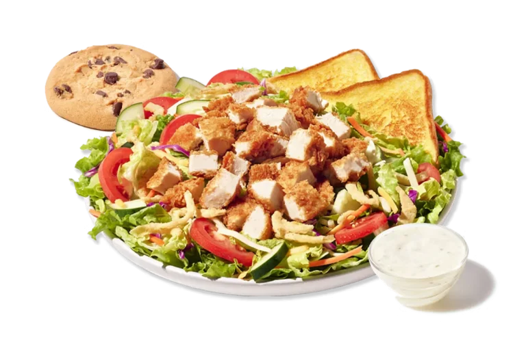 Zaxby's House Zalad Boxed Lunch, featuring a bed of mixed greens with carrots and red cabbage, topped with Cheddar Jack cheese, cucumbers, tomatoes, and fried onions, accompanied by fried or grilled chicken, Texas Toast, and a chocolate chip cookie.